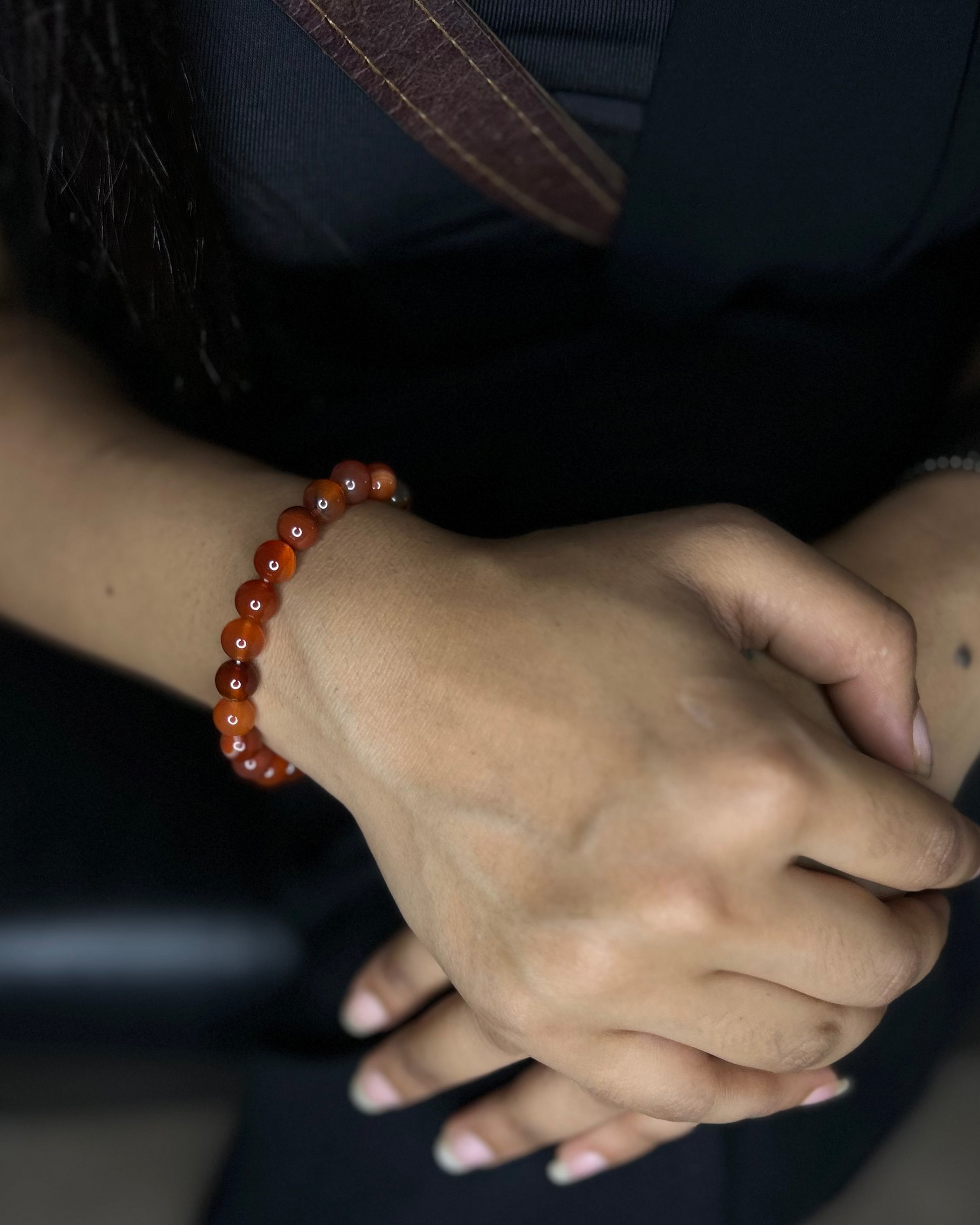 Close-up of hands with a red beaded bracelet on a dark background