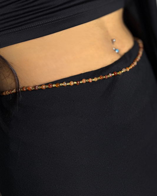 Close-up of a person wearing a black garment with a beaded belt.