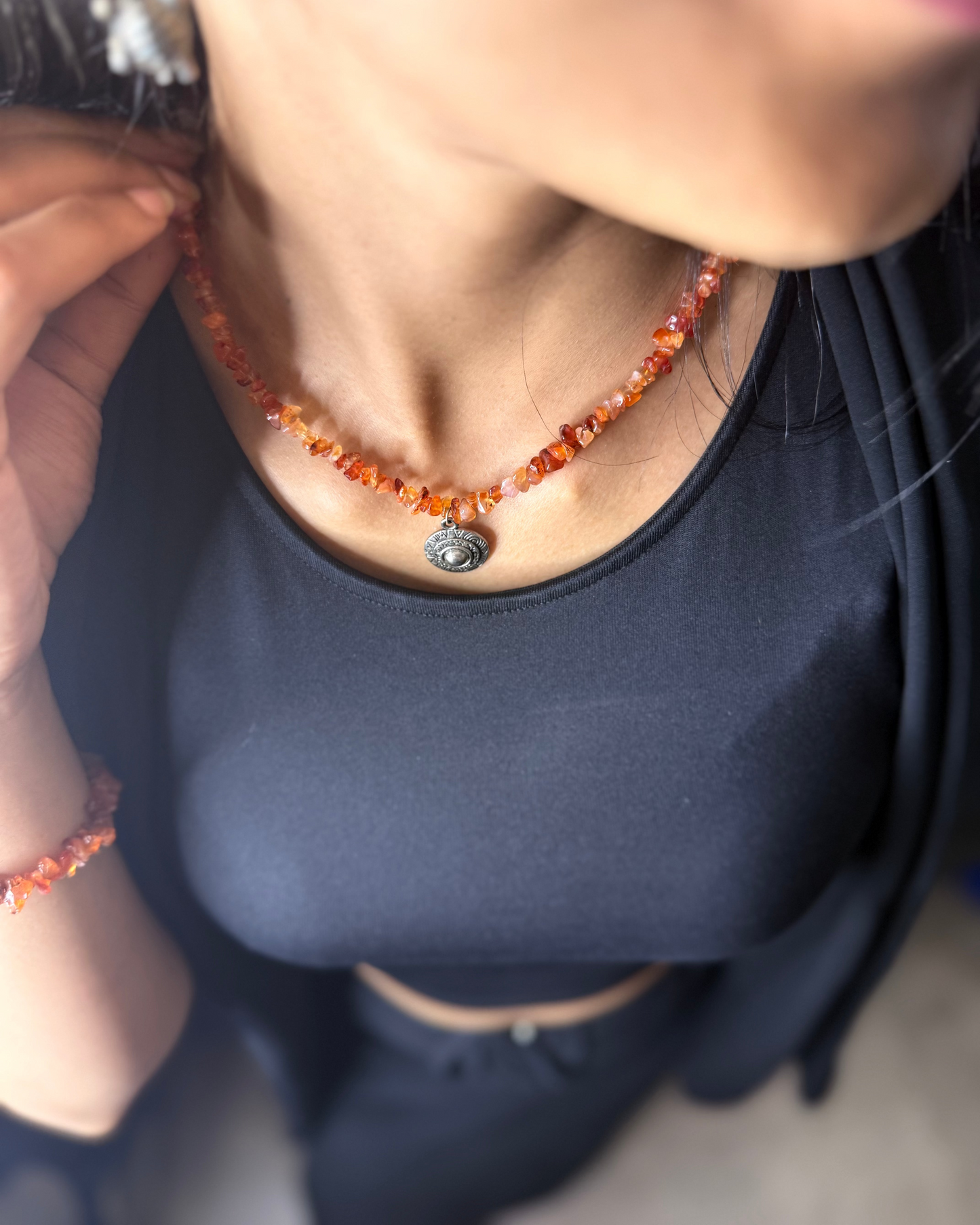 Person wearing a necklace with orange beads.