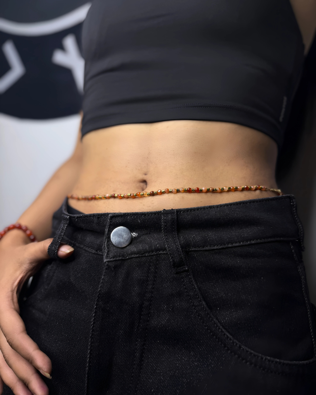 Person wearing a black crop top and black pants with carnelian beaded waist chain. 