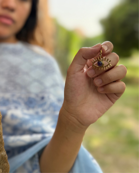 Person holding a gold evil eye earring 
