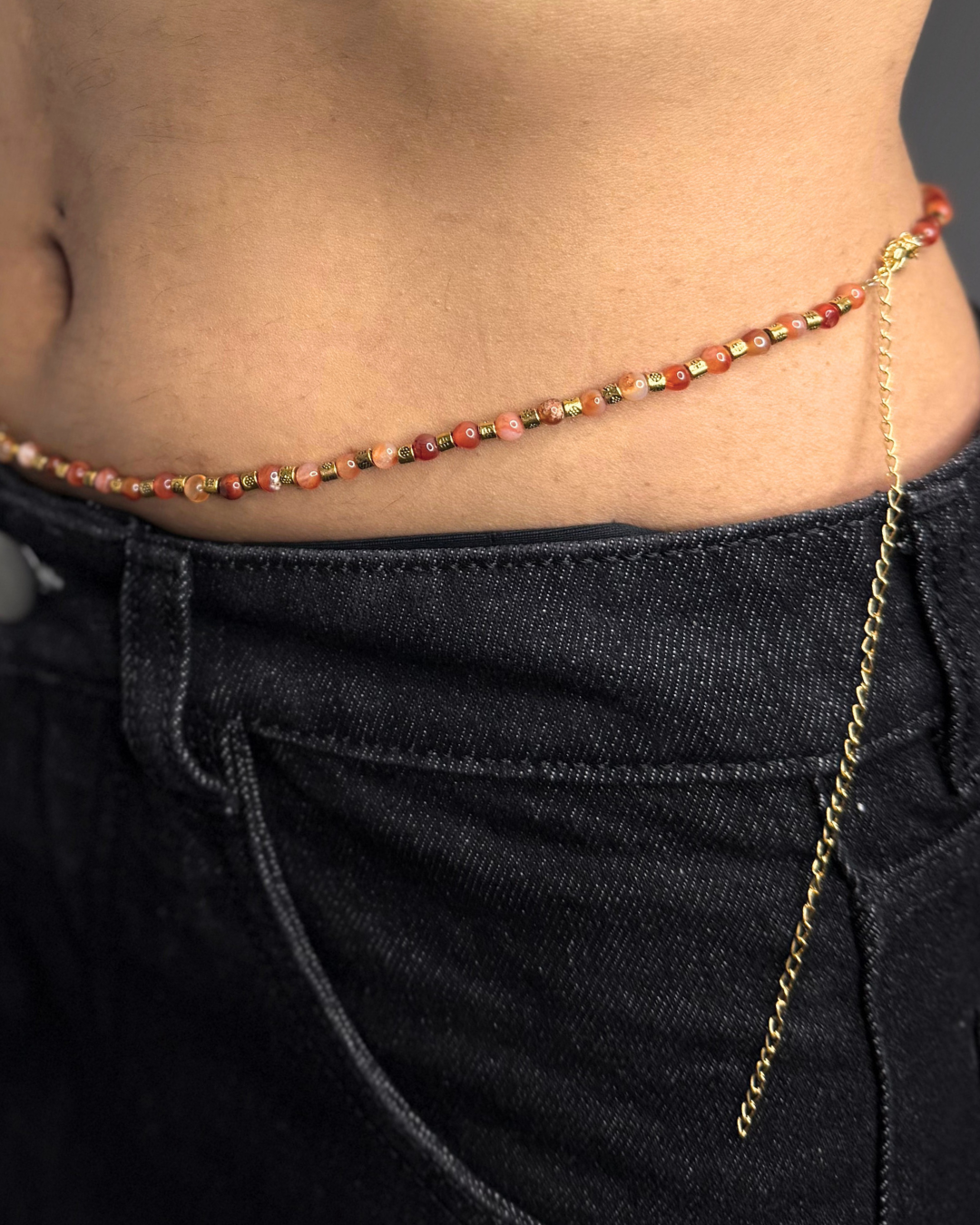 Close-up of a beaded waist chain worn with dark jeans.